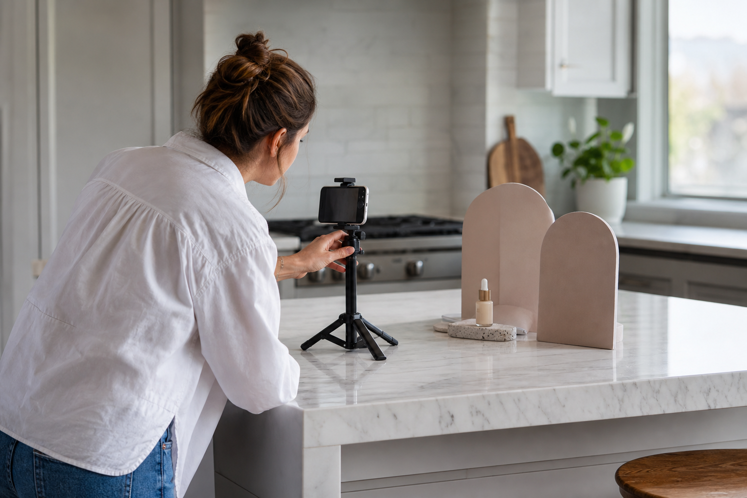 UGC creator filming a product on a phone tripod in a bright kitchen